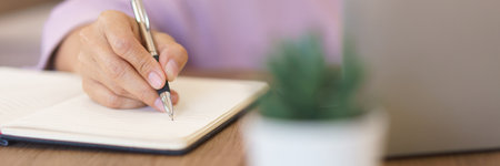 Female entrepreneur working at home to searching business data on laptop and writing notes in paper.の写真素材