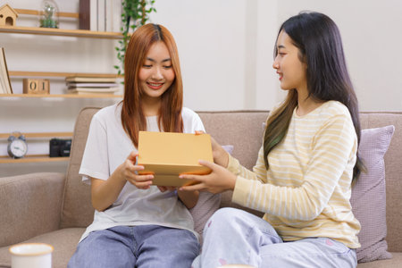 Activity at home concept, LGBT lesbian female is smiling while receiving gift box from girlfriend.の素材