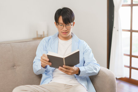 Business lifestyle, Businessman reading a book on couch to relaxation after working at home office.の写真素材