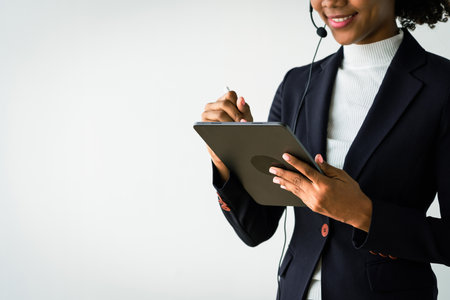 African american woman wearing headset and working on tablet while talking customer in call center.の写真素材