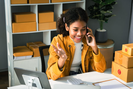 African american woman talking with customer on smartphone to checking online order and address.の写真素材