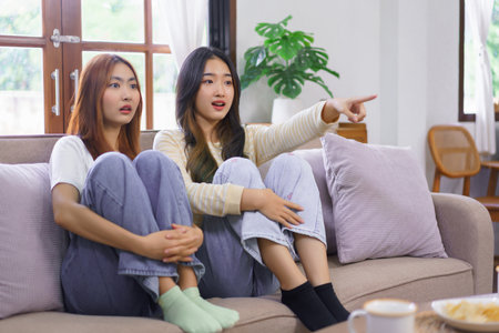 Activity at home concept, LGBT lesbian couple feel scared and pointing screen while watching movie.