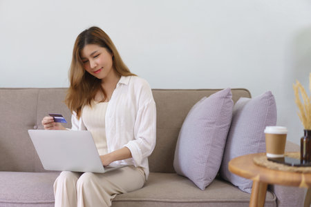 Business at home concept, Young Asian woman is typing credit card data on laptop to shopping online.