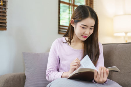 Women reading a book while sitting on big sofa to relaxation with happiness in lifestyle at home.の写真素材