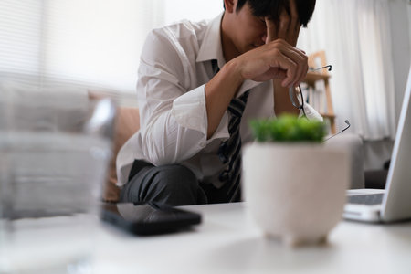 Businessman takes off glasses and cover face with hand while exhausted and stressed from overworked.の写真素材