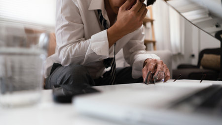 Businessman takes off glasses and massage nose while exhausted and stressed from overworked at home.の写真素材