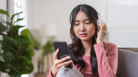 Women wearing headphone to watching movie on smartphone while leisure on sofa in lifestyle at home.の写真素材