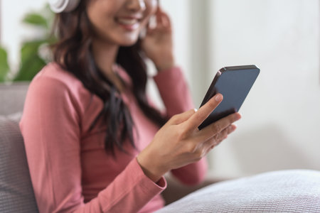 Women wearing headphone to watching movie on smartphone while leisure on sofa in lifestyle at home.の写真素材