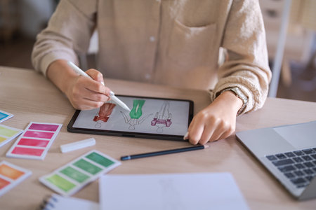 Fashion designer women work to designing dress and sketching on tablet for creative new collection.