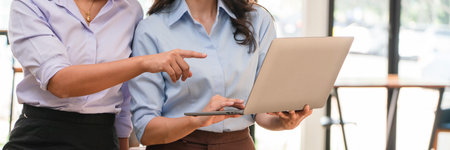 Two businesswomen reading finance data on laptop to discussing about marketing strategy of business.
