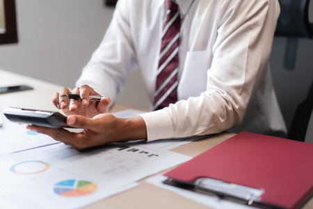 Businessman use calculator to calculate cost of project and checking marketing document of startup.の写真素材