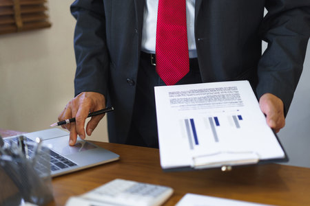 Business analysis concept, Senior businessman reading business chart and typing data on laptop.