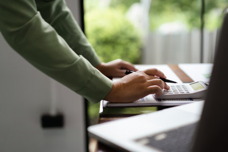Female accountant use calculator to calculate number on document for accounting finance of business.