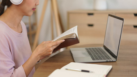 Female entrepreneur in headphone to listening music and working at home with reading business book.の写真素材