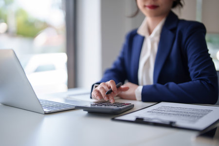 Businesswomen checking finance data on document and finance chart on digital laptop with calculator while working to analysis strategy investment and management about new startup project in workplace.の写真素材