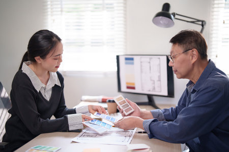 Interior designer women explaining blueprint of construction architectural and color swatch samples...