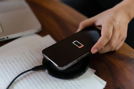 Hands of businessman putting smartphone on wireless charger device to charging battery mobile phone.