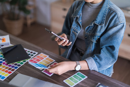 Graphic designer women taking photo color swatch samples on smartphone for designing graphic design.の写真素材
