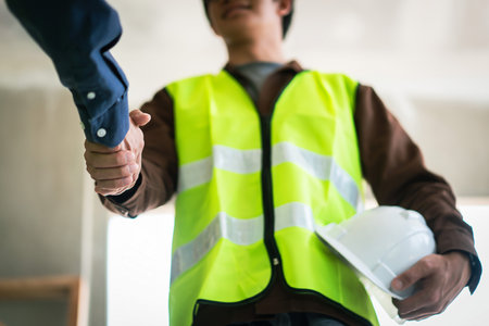 Two engineers shaking hands after working successfully about building of construction site.