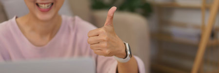 Female entrepreneur meeting and showing thumb up with partners in video call while working at home.