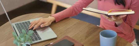 Young businesswoman working at home to searching business data on laptop and checking in notebook.の写真素材
