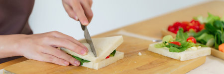 Asian women making delicious sandwich with vegetables and mayonnaise to cutting sandwich with knife...