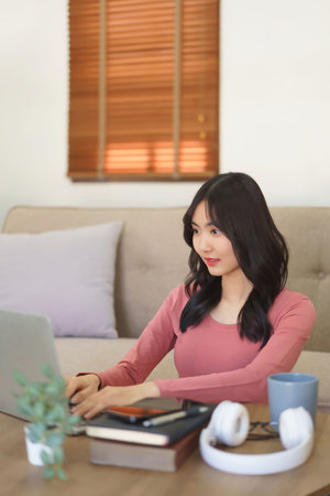 Young businesswoman thinking new project and typing business report on laptop while working at home.の写真素材