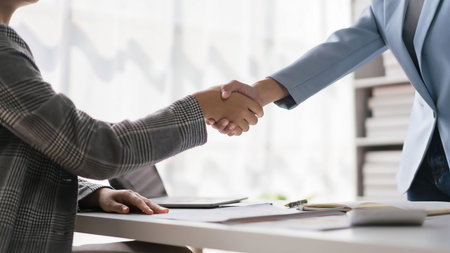 Two businesswoman greeting and shaking hands while discussion about new business project together.の写真素材