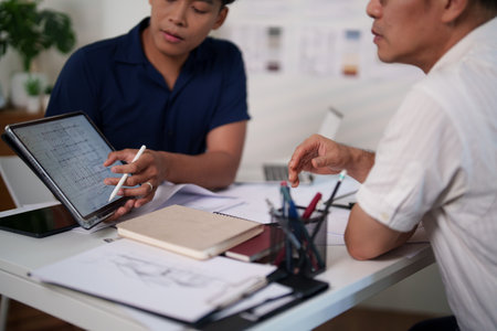 Engineers discussing construction plans at the desk with blueprints and calculators, focusing on project strategies and material estimates.の写真素材
