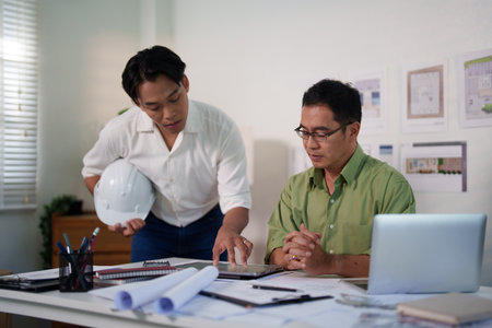 Engineering professionals calculating material quantities for a construction project using laptops and notepads.の写真素材