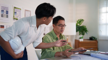 Engineering professionals calculating material quantities for a construction project using laptops and notepads.の写真素材