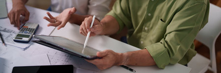 Engineers pointing at architectural drawings and discussing the details of material requirements.の写真素材