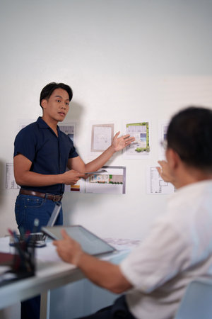 A group of engineers reviewing structural designs and material specifications at a meeting table.の写真素材