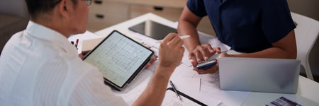 A group of engineers reviewing structural designs and material specifications at a meeting table.の写真素材