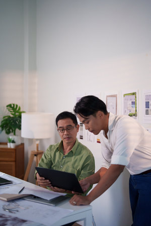 A team of engineers evaluating project risks and discussing construction timelines at their...