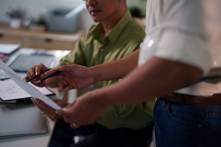 A team of engineers evaluating project risks and discussing construction timelines at their workspace.の写真素材