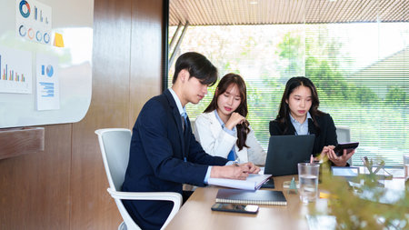 Young startup professionals discussing business data on a laptop, analyzing financial growth and...