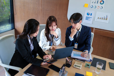 Young startup professionals discussing business data on a laptop, analyzing financial growth and...