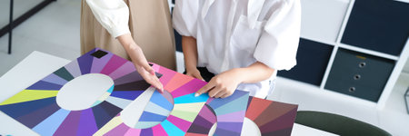 Two Asian women, adult, in a bright studio analyzing personal color using color swatches. They are choosing the best seasonal palette. Discover ideal shades for your wardrobe and makeup.の写真素材