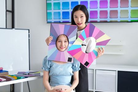 Two Asian women, one young adult client and one adult consultant, are doing personal color analysis to find the best colors for the client's complexion and skin tone in a professional studio setting.の写真素材