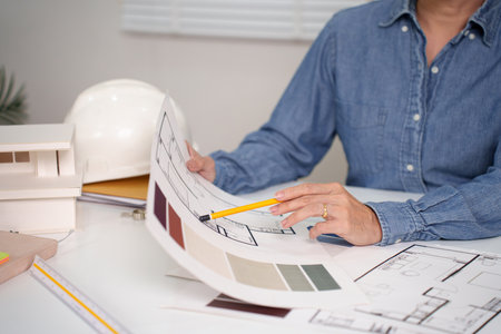 Adult Asian Hand Drawing Blueprint for House Project. Architect reviewing blueprint for interior design plans. Architect analyzing building design document for construction project. Examining Hand Drawing Blueprint for house project.の写真素材