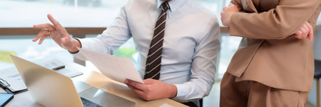 Adult asian business people collaborate strategy review documents laptop computer bright modern office space professional environmentの写真素材