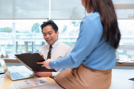 Adult Asian colleagues analyze business data review reports discuss project details during collaborative meeting office environment.の写真素材