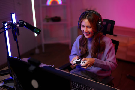 Asian woman streams games live. Uses controller headset mic computer. Home studio RGB lights....