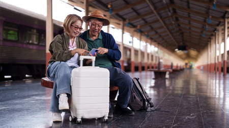 Senior Asian travelers train station platform smartphone booking journey plan trip explore vacation together looking screen planning trip.の写真素材