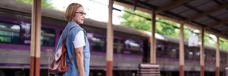 Asian woman waits train station platform ready solo adventure travel journey by rail vacation transportation lifestyleの写真素材