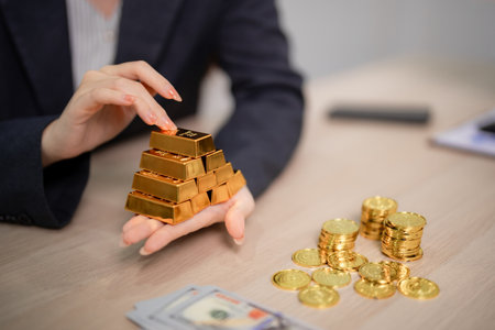Professional Asian woman hand holding shiny gold bars showcasing investment wealth precious metal...