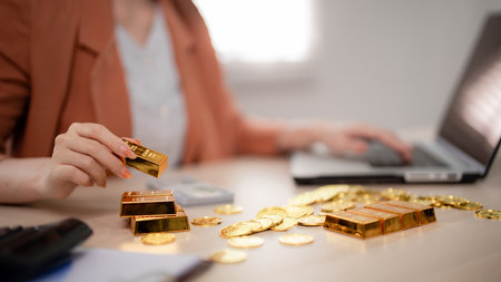 Adult Asian woman actively managing gold investments and trading precious metals. She calculates...