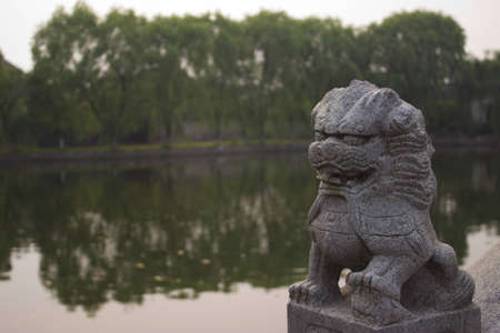 Chinese Lion Statue in Front of a Pondの写真素材