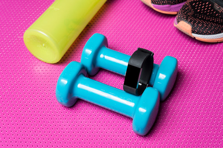 Fitness band, weights, running shoes and a biddon on an exercise matの写真素材